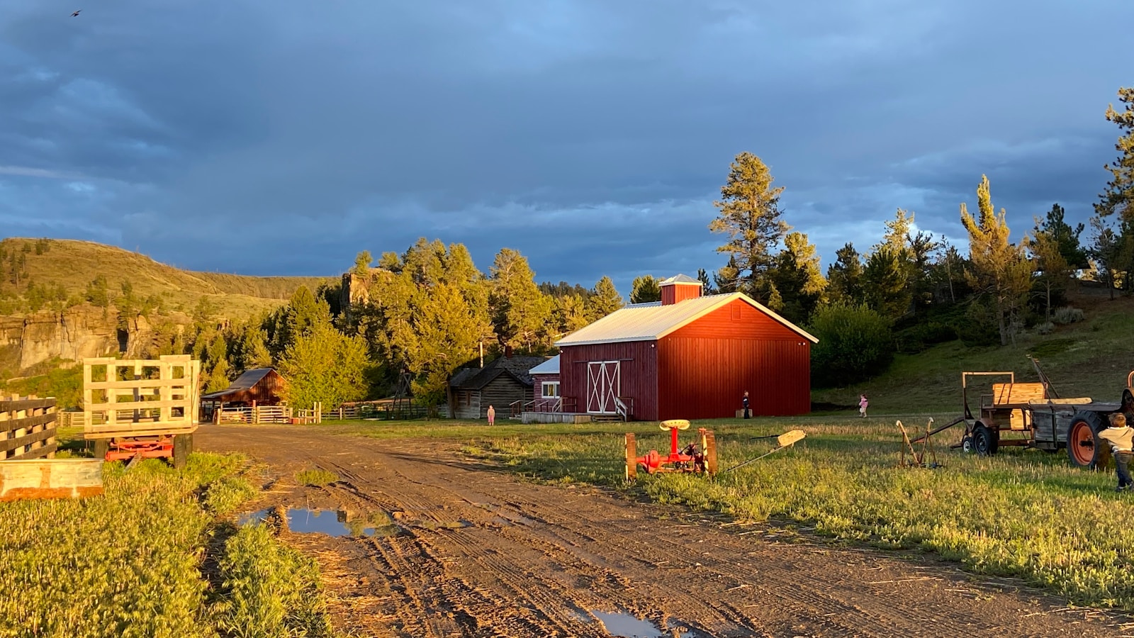 red wooden barn near green trees under white clouds during daytime